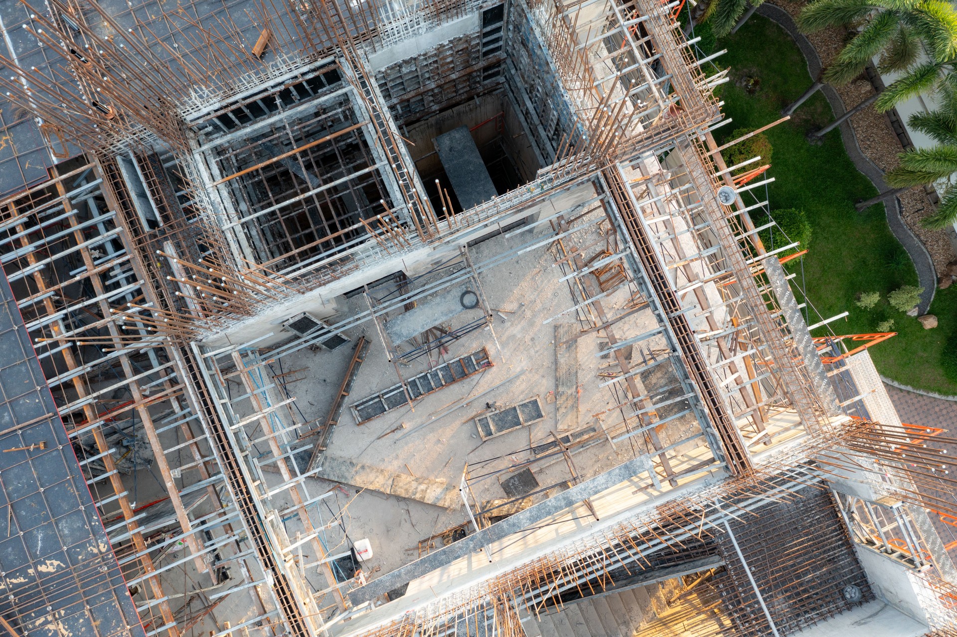 Aerial view of construction site showing rebar, concrete, and formwork, revealing the building's layout.
